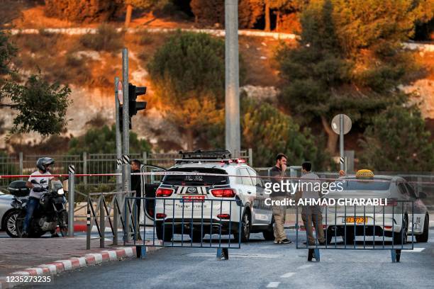 This picture taken on September 15, 2021 shows a view of a taxi parked by an Israeli police vehicle manning a checkpoint on a road linking the east...