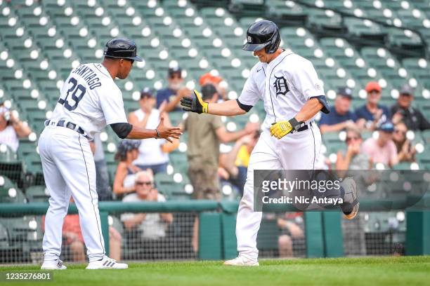Dustin Garneau of the Detroit Tigers rounds the bases after hitting a solo home run and high fives Ramon Santiago of the Detroit Tigers against the...