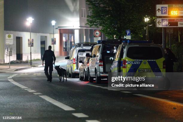 September 2021, North Rhine-Westphalia, Hagen: A policeman leads a dog through a street where a Jewish community building is located. Numerous police...