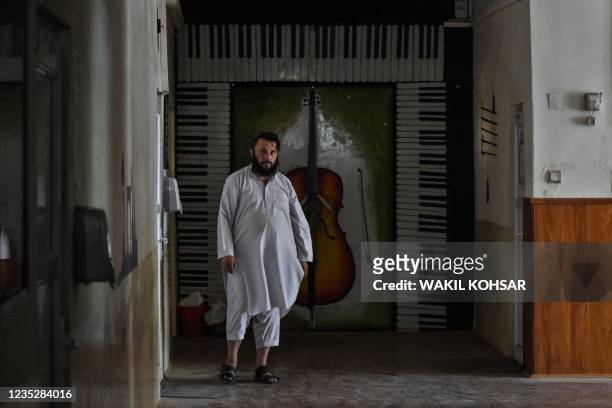 This photo taken on September 14, 2021 shows a member of the Taliban walking in a corridor at the Afghanistan National Institute of Music in Kabul. -...