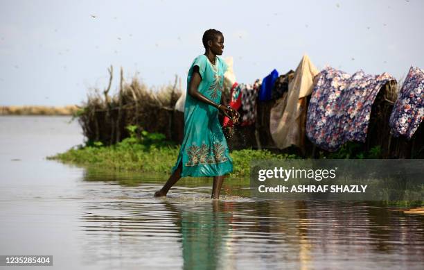 South Sudanese refugee walks in flooded waters from the White Nile at a refugee camp which was inundated after heavy rain near in al-Qanaa in...