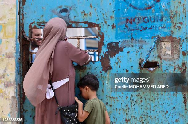 Palestinian woman and her child stand next to a window of an aid distribution centre run by the United Nations Relief and Works Agency in Gaza City,...