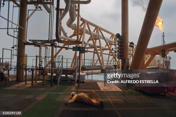 An oil worker lies on a deck during a fire drill aboard the Pemex Ku-S oil processing center, part of the Ku-Maloob Zaap complex, in the Gulf of...