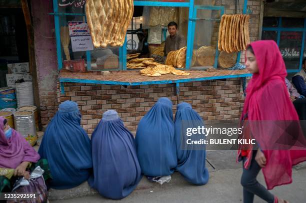 Burqa-clad women wait for free bread in front of a bakery in Kabul on September 16, 2021.