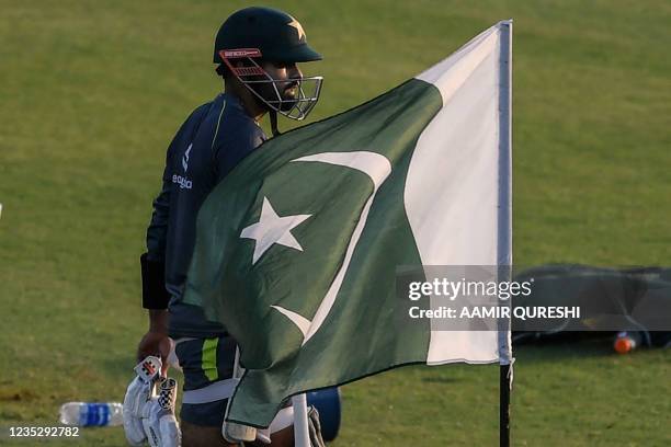 Pakistan's captain Babar Azam walks past a national flag as he arrives to bat during a practice session at the Rawalpindi Cricket Stadium in...