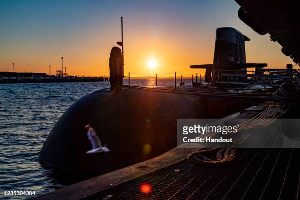 In this handout image provided by the Australian Defence Force, the sun rises over a Royal Australian Navy submarine berthed at HMAS Stirling on...