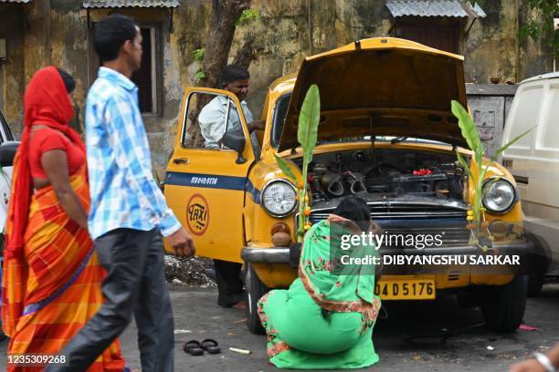 An owner of Ambassador taxi decorates the car on the occasion of the Hindu festival of Vishwakarma Puja in Kolkata on September 17, 2021.