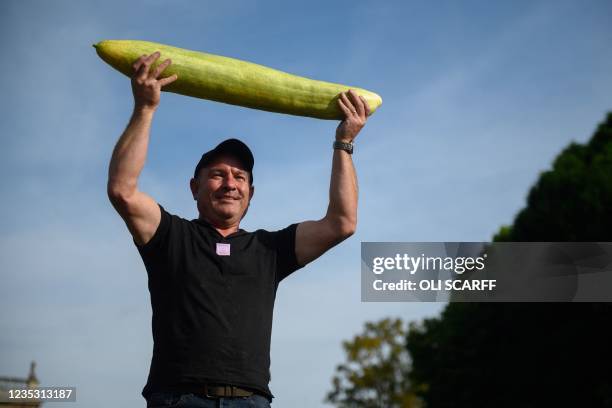 Grower John Simpson poses with his huge cucumber measuring 88cm long after it achieved 1st place in the giant vegetable competition on the first day...