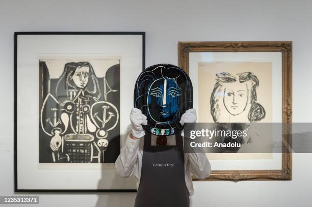 Gallery staff member holds 'Visage de femme' by Pablo Picasso , estimate: Â£15,000 - 25,000 in front of PIcasso artworks 'Femme au Fauteuil No. 4',...
