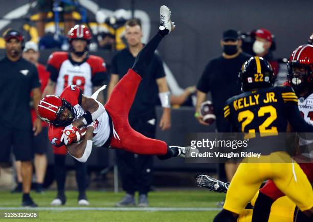 Markeith Ambles of the Calgary Stampeders is is tripped up while running with the ball during a CFL game against the Hamilton Tiger-Cats at Tim...