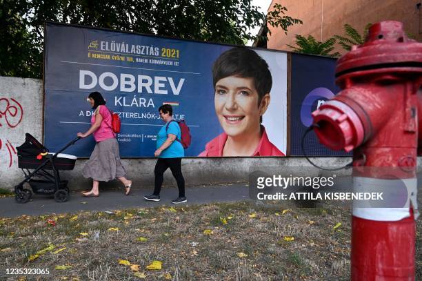 Women walk past a billboard with a campaign poster featuring Vice President of the European Parliament and candidate for prime minister Klara Dobrev...