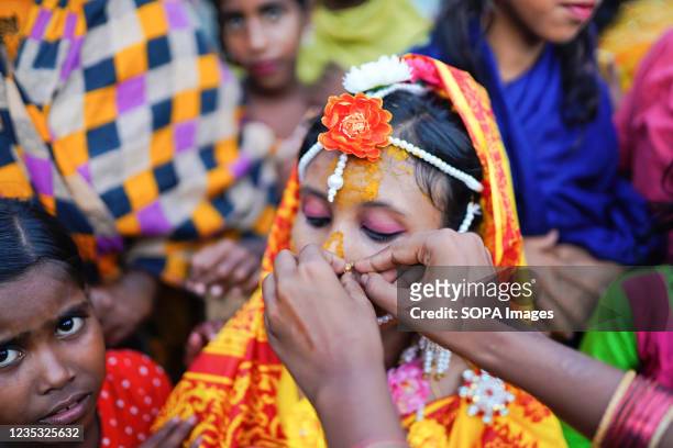 Relative helps to adjust ornaments of 14 year old school going girl Hafsa on her wedding day at a village named Joymoni from a coastal area from...