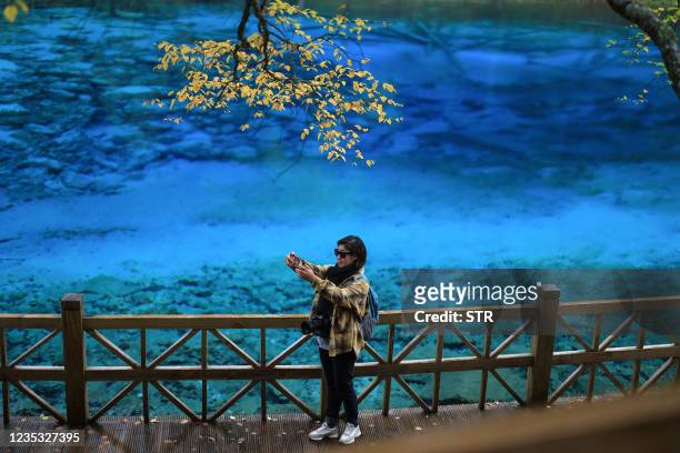 This photo taken on September 17, 2021 shows a tourist taking selfie at Jiuzhaigou Valley in Aba in China's southwestern Sichuan province. - China...