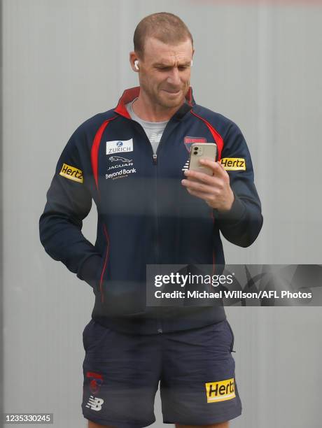 Simon Goodwin, Senior Coach of the Demons takes a call during the Melbourne Demons training session at Lathlain Park on September 18, 2021 in Perth,...