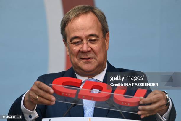 Christian Democratic Union leader and chancellor candidate Armin Laschet puts the CDU logo back on the lectern as he addresses supporters during an...