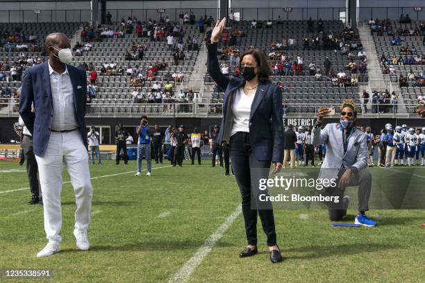 Vice President Kamala Harris, center, waves after flipping a coin as Wayne A. I. Frederick, president of Howard University, watches ahead of the...