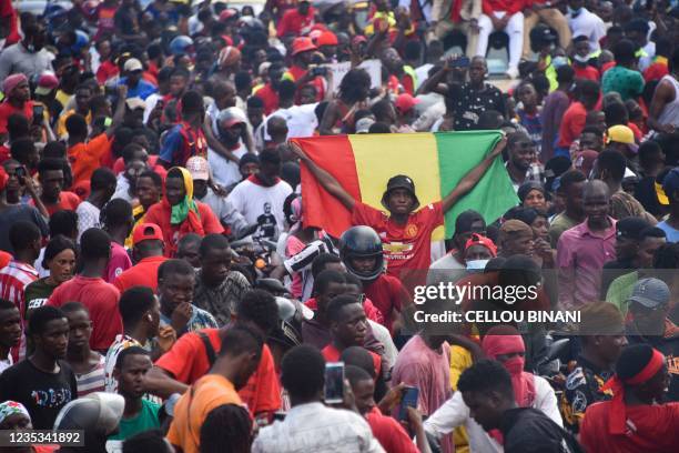 Supporter holds up a Guinean National Flag as exiled activists arrive in Conakry, on September 18, 2021. - Guinea's ruling junta on September 18,...