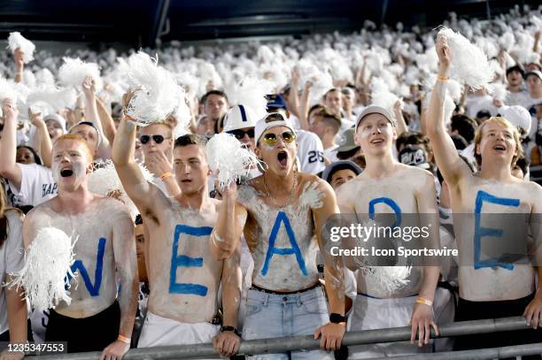 Penn State students and fans painted with body paint spelling We Are cheer and wave pom poms and cheer in the student section during the whole...