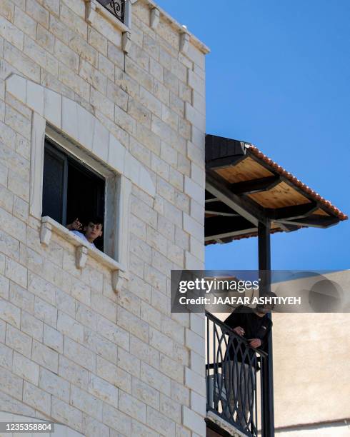 Boy looks out a window while another man stands in a nearby balcony in a Palestinian house in Jenin in the north of the occupied West Bank on...