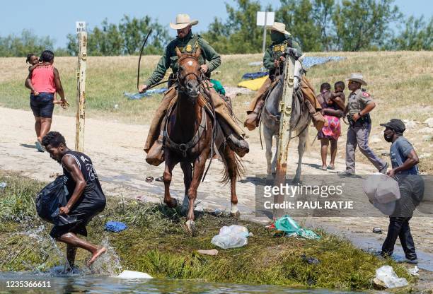 United States Border Patrol agents on horseback try to stop Haitian migrants from entering an encampment on the banks of the Rio Grande near the...