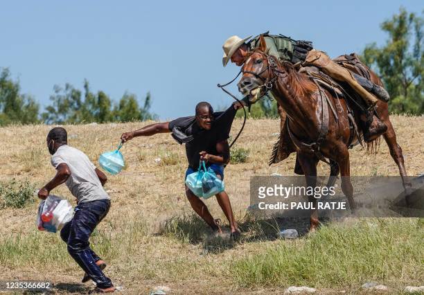 United States Border Patrol agent on horseback tries to stop a Haitian migrant from entering an encampment on the banks of the Rio Grande near the...