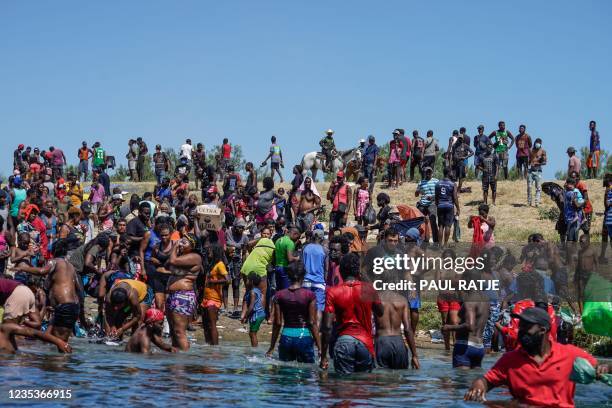 Haitian migrants, part of a group of over 10,000 people staying in an encampment on the US side of the border, cross the Rio Grande river to get food...