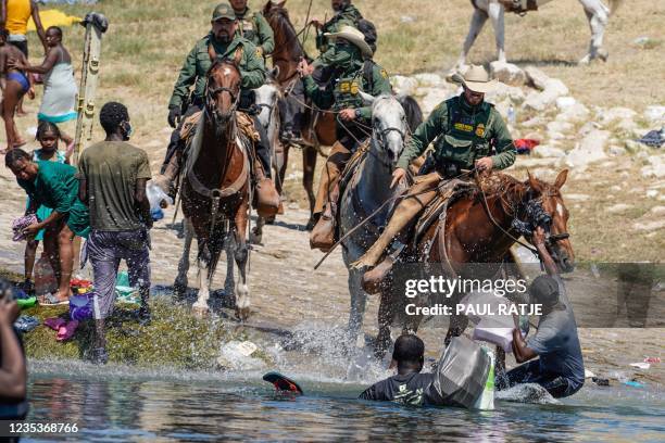 United States Border Patrol agents on horseback tries to stop Haitian migrants from entering an encampment on the banks of the Rio Grande near the...