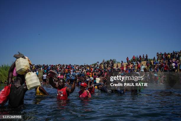 Haitian migrants, part of a group of over 10,000 people staying in an encampment on the US side of the border, cross the Rio Grande river to get food...