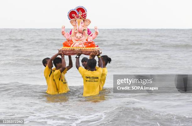 Volunteers carry an idol of a Hindu elephant-headed god Ganesh for immersion at Juhu beach in Mumbai. Devotees immerse the idol of Hindu...