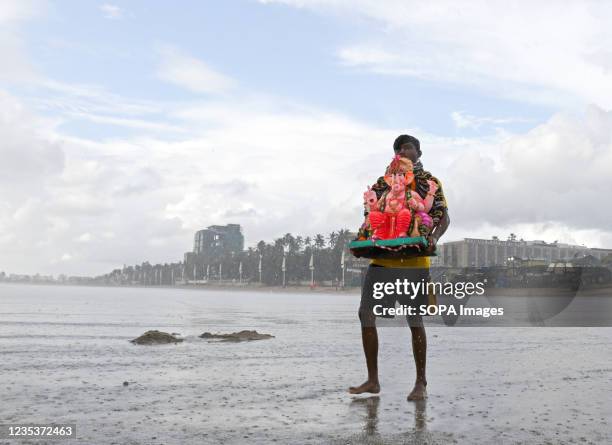 Volunteer carries an idol of a Hindu elephant-headed god Ganesh for immersion at Juhu beach in Mumbai. Devotees immerse the idol of Hindu...