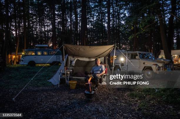 This picture taken on September 19, 2021 shows campervan enthusiast Nobuyuki Ito taking a rest in front of his 1974 Volkswagen Type 181 - Thing at a...