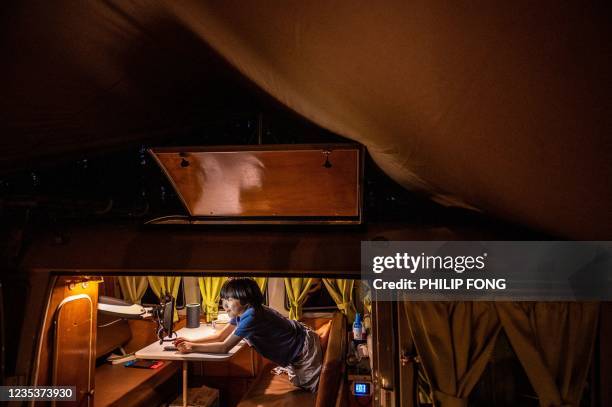 This picture taken on September 19, 2021 shows campervan enthusiast Takayuki Minagawa making dinner as his son Rintaro Minagawa watches a video on a...