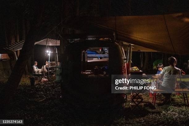 This picture taken on September 19, 2021 shows campervan enthusiast Takayuki Minagawa having dinner with his son Rintaro Minagawa next to a 1964...