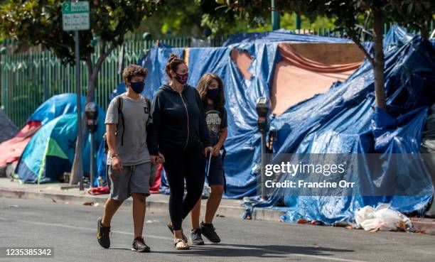 Sarah Tindall, middle, walks her sons Dylan and River past a homeless encampment near Larchmont Charter School - Selma located in the Hollywood...