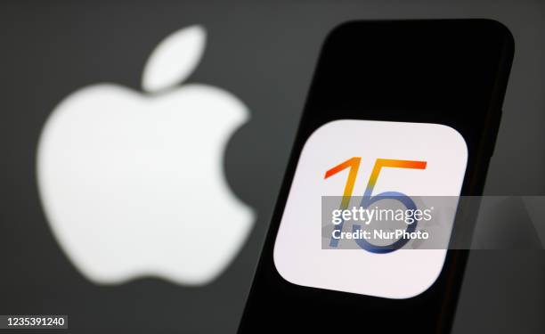 IOS 15 logo displayed on a phone screen and Apple logo in the background are seen in this illustration photo taken in Krakow, Poland on September 21,...