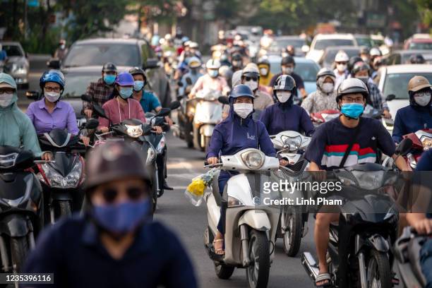People wearing face masks commute on their motorbikes during the morning peak hour on September 21, 2021 in Hanoi, Vietnam. Authorities have allowed...
