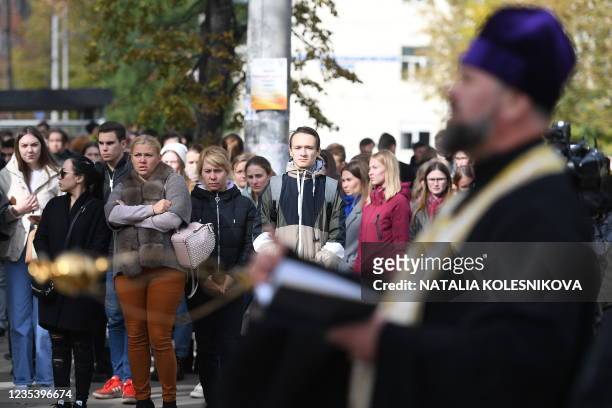 Attendees stand as Russian Orthodox priest services at the entrance of the university campus in Perm on September 21, 2021 one day after a gunman...