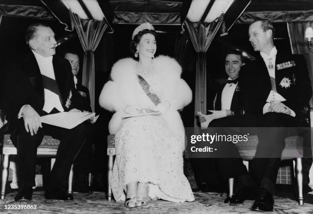 Queen Elizabeth II flanked the Duke of Edinburgh and French President Rene Coty seats aboard the "Borde Fretigny" boat in Paris during a state visit...