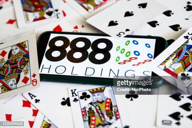 Holdings logo displayed on a mobile phone and playing cards are seen in this illustration photo taken in Krakow, Poland on September 21, 2021.
