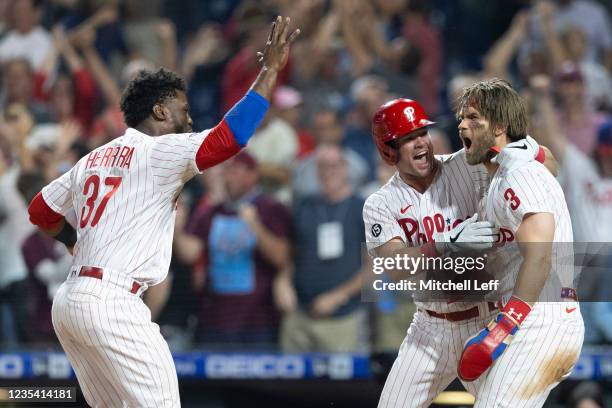 Bryce Harper of the Philadelphia Phillies celebrates with Andrew Knapp and Odubel Herrera after scoring the game-winning run in the bottom of the...