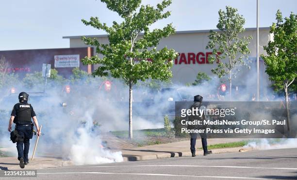 Police officers walk among tear gas canisters as they try to clear the parking lot of a Target store in St. Paul's Midway neighborhood Thursday, May...