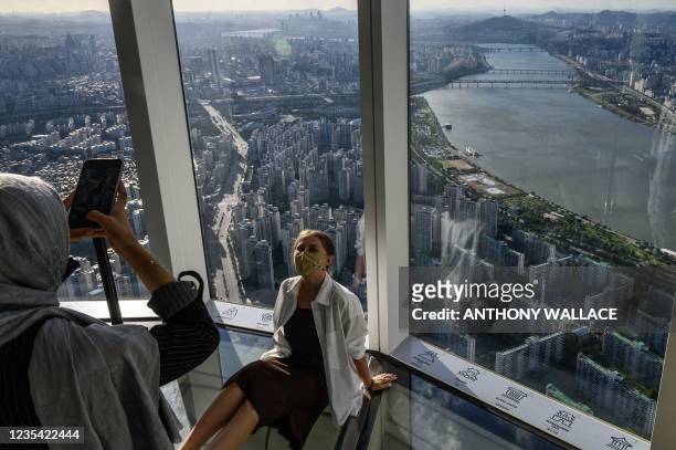 Visitors pose for photos on a glass floored section of the 123-story Lotte World Tower skyscraper in Seoul on September 22, 2021.