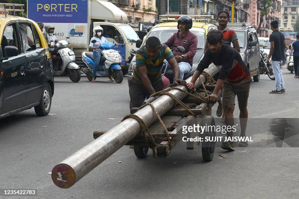 Men push a loaded handcart along a street in Mumbai on September 22, 2021.