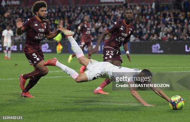 Paris Saint-Germain's Moroccan defender Achraf Hakimi falls as he fights for the ball with Metz's French defender Matthieu Udol during the French L1...