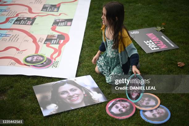 Gabriella Ratcliffe, daughter of jailed British Iranian aid worker Nazanin Zaghari-Ratcliffe moves portraits of her mother on a giant snakes and...