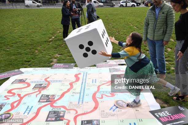 Gabriella Ratcliffe, daughter of jailed British Iranian aid worker Nazanin Zaghari-Ratcliffe rolls a dice to play on a giant snakes and ladders board...