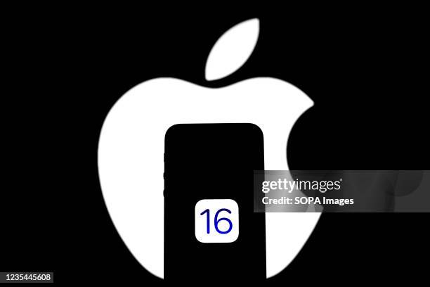 In this photo illustration IOS 16 logo seen displayed on a Apple iPhone with an Apple logo in the background.