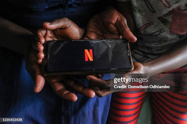 Woman and her son wait as the Netflix account app loads on their android smartphone on September 23, 2021 in Nairobi, Kenya. This week, the...