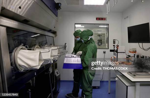 Lab technicians work on a process machine to produce CAR-T cells and RNA in the laboratory of French biopharmaceutical company Cellectis in Paris on...