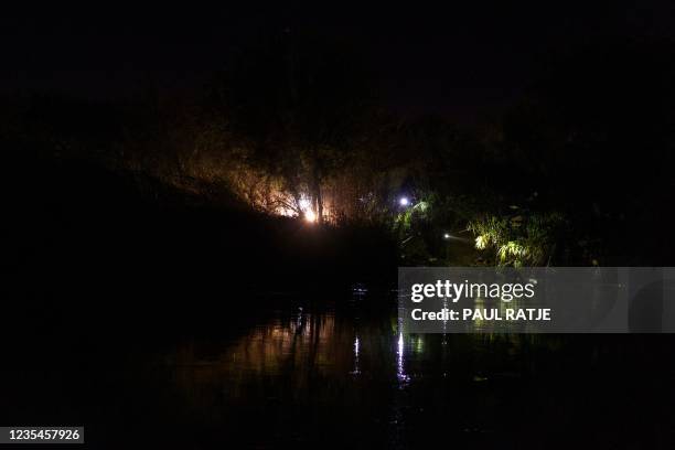 Light is reflected on the water as United States Border Patrol agents search the banks of the Rio Grande in Del Rio, Texas, as seen from Ciudad...